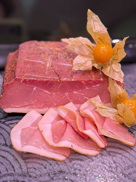 Herzhafter Schinken-Speck aus regionaler Schweinekeule, trocken gepökelt, monatelang gereift und über Buchenholz geräuchert – kräftig im Geschmack mit feiner Würze.